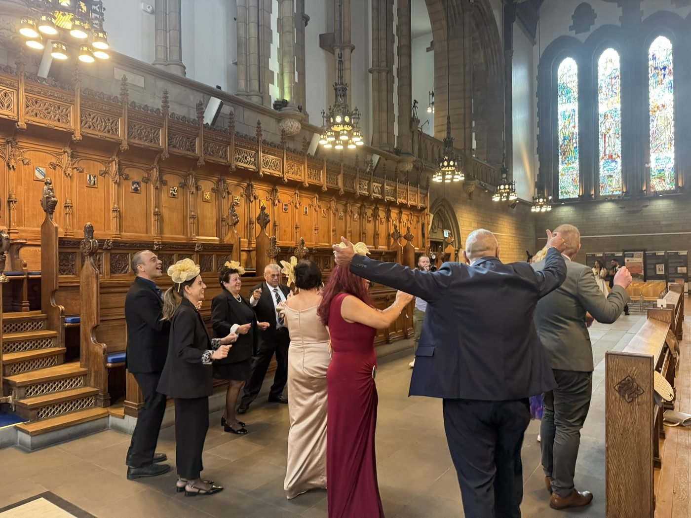 The interior of the University of Glasgow Memorial Chapel, carved wooden stalls along both sides and Douglas Strachan's stained glass windows above