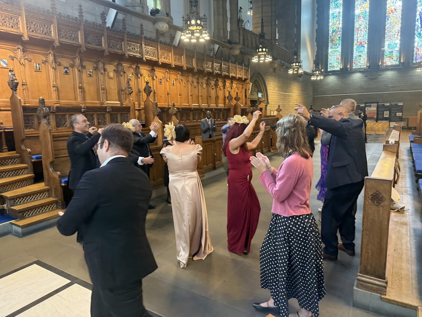 Wedding guests dancing together in a circle in the University of Glasgow Memorial Chapel after the ceremony