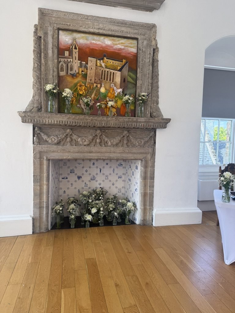 An ornate historic fireplace at West Lothian Burgh Halls dressed with white flowers ahead of a wedding ceremony