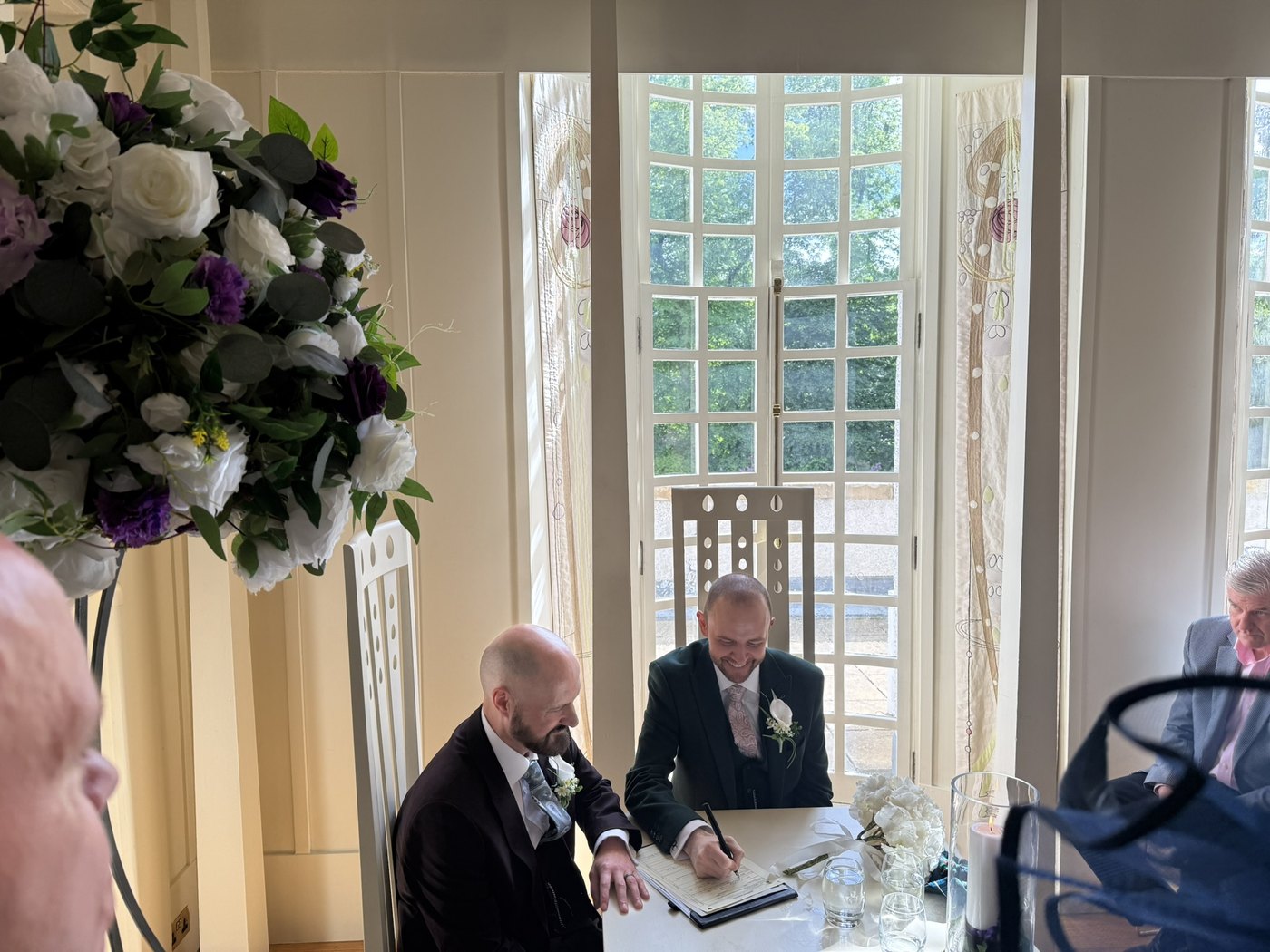 Chris and David signing their Marriage Schedule at House for an Art Lover, Glasgow, in front of tall Mackintosh-style windows