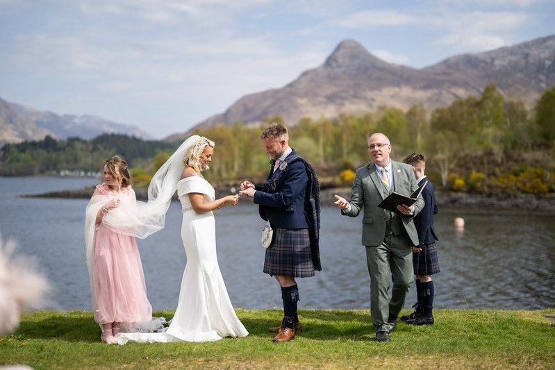 Colin and Lisa Marie exchange rings during their humanist ceremony on the shore of Loch Leven, celebrant John Paul Fitzpatrick officiating, the Isles of Glencoe behind