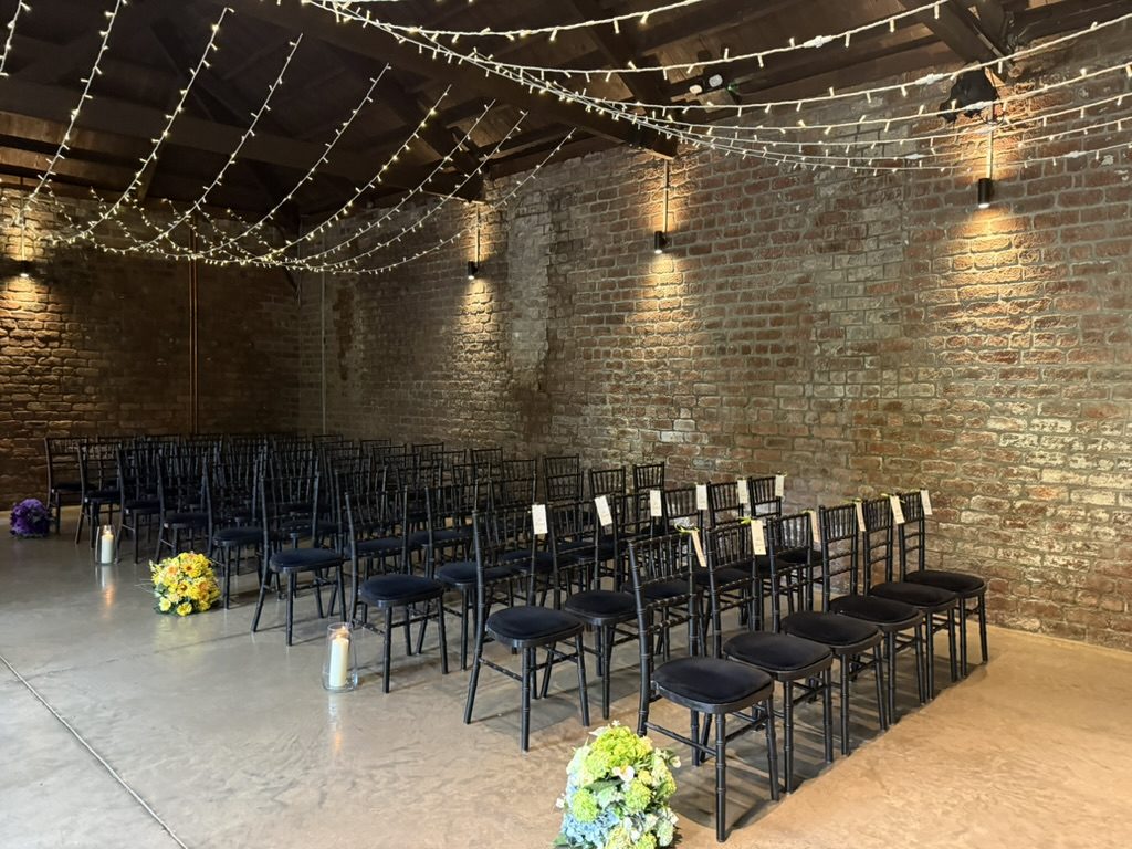 The Engine Room at The Engine Works dressed for a ceremony — exposed brick, fairy lights strung overhead, chiavari chairs set out
