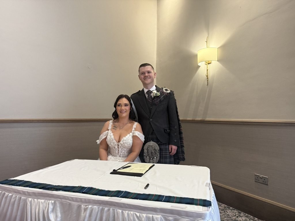 A newly married couple with celebrant John Paul at the signing table in the function room at Riverside Lodge Hotel, Irvine