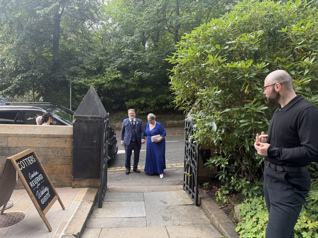 Guests arriving through the garden gate at Cottiers, a blackboard sign reading Cottiers garden reserved for wedding guests