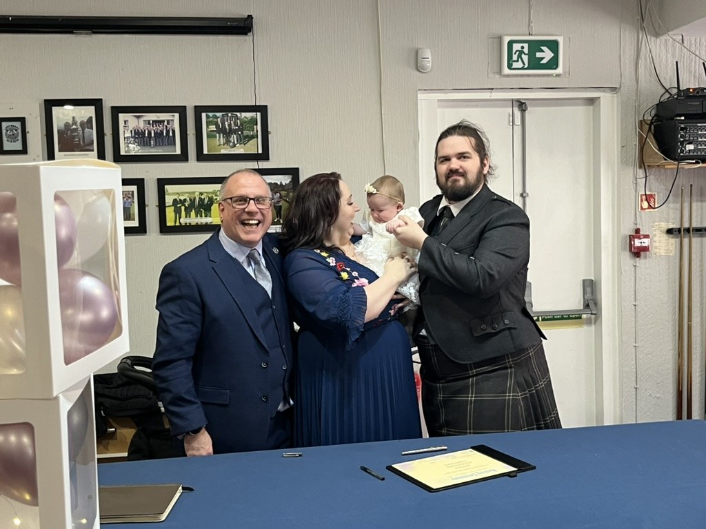 John Paul with a family, celebrating their daughter's naming certificate signing at a humanist naming ceremony in Inverclyde