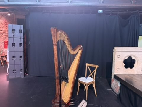 A concert harp and chair set up on the stage at Cottiers before the ceremony